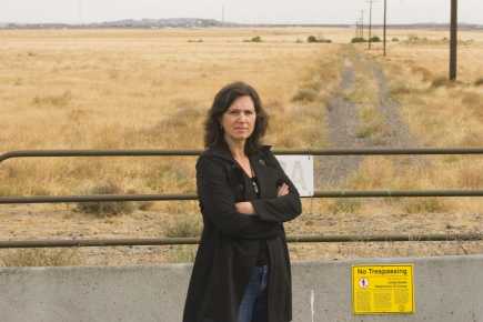 Kathleen Flenniken standing with arms crossed at Hartford. She is standing in front of barrier with a small sign that reads “No Trespassing”