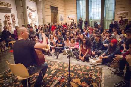 Musician Perhat Khaliq performing with acoustic guitar in front of a crowd