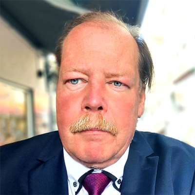 A close-up image of Andreas Kablitz looking to the left of the camera while wearing a suit and tie.