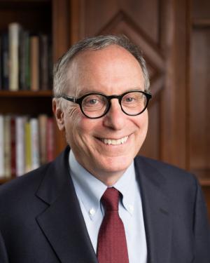 Jonathan Lear looks into the camera while wearing a suit and tie and glasses.