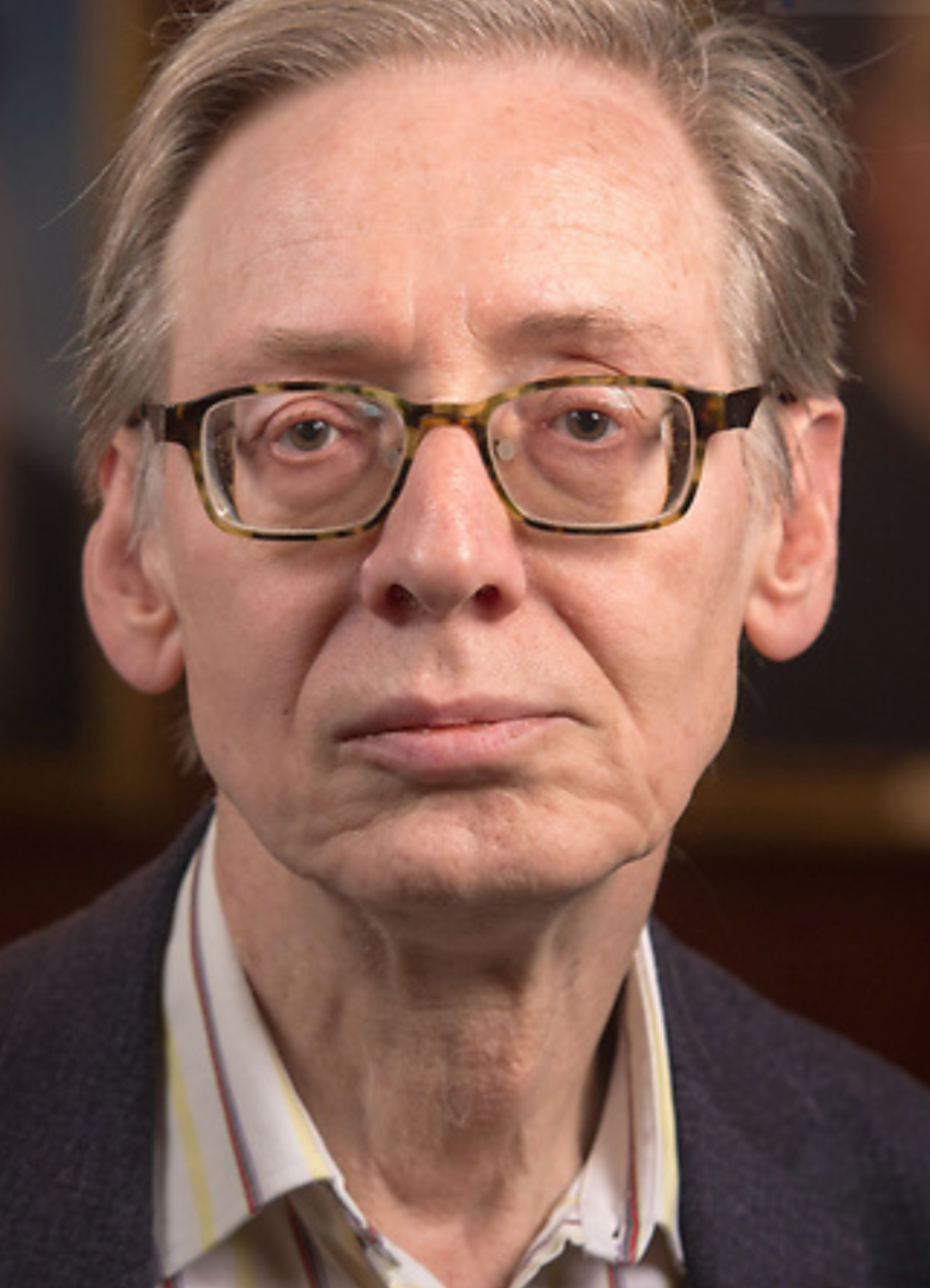 A close up image of Stephen Gersh looking into the camera while wearing glasses and a collared shirt and jacket.