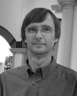 A black and white photo of Stephen Hinds wearing glasses.