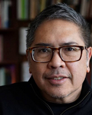 A close-up image of Vicente Rafael wearing glasses and a dark shirt in front of a bookcase.