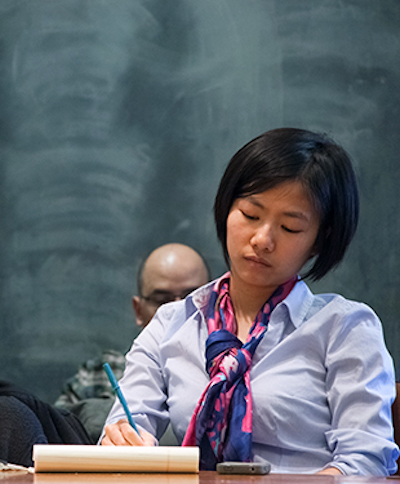 Scholar at a desk in front of a chalkboard