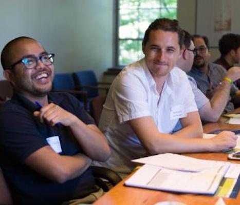 two cohort members laughing together at conference table