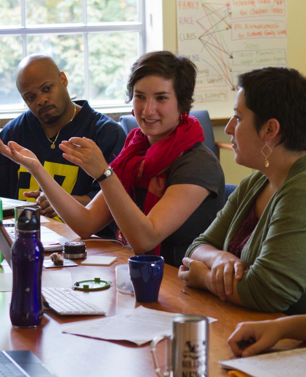 3 scholars at a conference table in active discussion