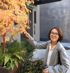 Portrait of Xin Peng standing by a golden Japanese Maple tree