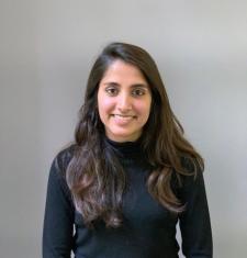 Smiling head shot of a woman with long dark brown hair wearing a long sleeved black turtleneck sweater.