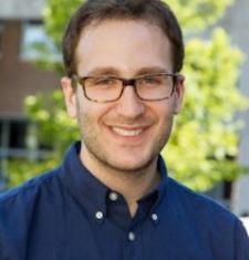 Portrait of Daniel Bessner in a blue shirt and glasses