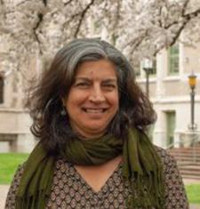 Davinder Bhowmik stands outside wearing a green scarf and patterned shirt.
