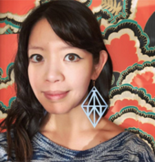 Jane Wong stands in front of a patterned wall wearing a grey shirt.