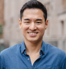 Jang Wook Huh stands outside in front of a building wearing a blue shirt.