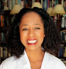 A portrait of Jasmine Mahmoud standing in front of a bookcase.