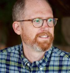 Jeffrey Knight wears a plaid shirt and glasses.