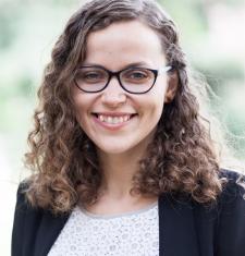 Liina-Ly Roos wears glasses, a white shirt, and a black jacket.