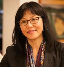 Portrait of Madeleine Dong wearing glasses, a scarf, and a dark jacket.