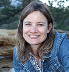 Minda Martin sits outside wearing a denim jacket and patterned shirt.