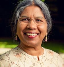 Priti Ramamurthy stands outside wearing glasses and a floral shirt.