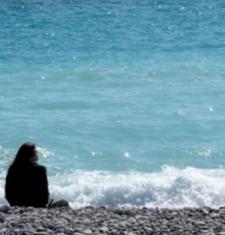 Sarah Ross sits on a beach looking toward the water.