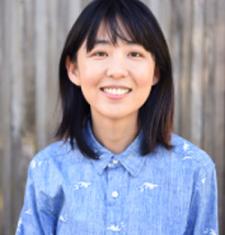 Portrait of Ellen Y. Chang standing in front of a blurred background and wearing a blue collared shirt.