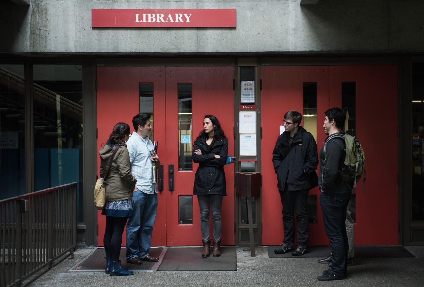 Students stand outside a library at a community college.