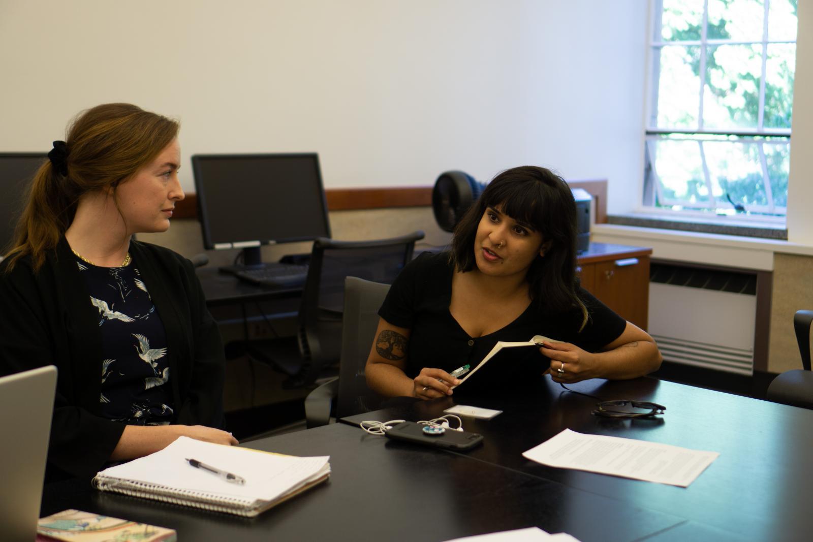 Two people sit at a table and talk to each other.