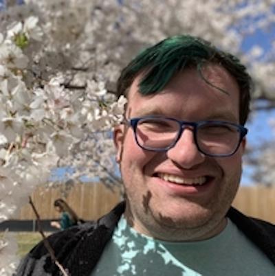 Close-up of Julian Barr smiling among cherry blossoms