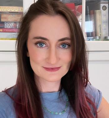 Close-up portrait of a white woman with pink and brown hair and blue eyes wearing a blue shirt