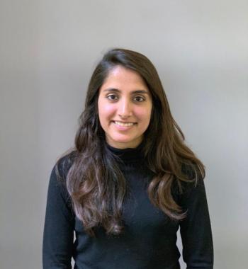 Smiling head shot of a woman with long dark brown hair wearing a long sleeved black turtleneck sweater.