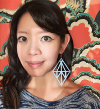 Jane Wong stands in front of a patterned wall wearing a grey shirt.