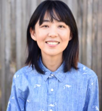 Portrait of Ellen Y. Chang standing in front of a blurred background and wearing a blue collared shirt.