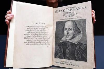 Photo of a person holding a large book open for the camera with a drawing of Shakespeare on the page.