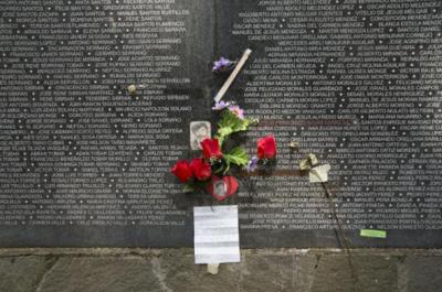 A bouquet of flowers sits at the base of a dark wall with names etched in white.