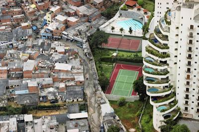 Photo of an apartment complex with tennis courts and pools walled off from an area of lower-income housing.