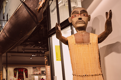 Welcome figure and canoe positioned in Burke Museum's Northwest Native Art gallery.