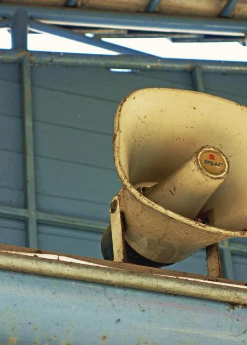 A megaphone mounted on a blue-gray wall.