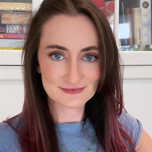 Close-up portrait of a white woman with pink and brown hair and blue eyes wearing a blue shirt