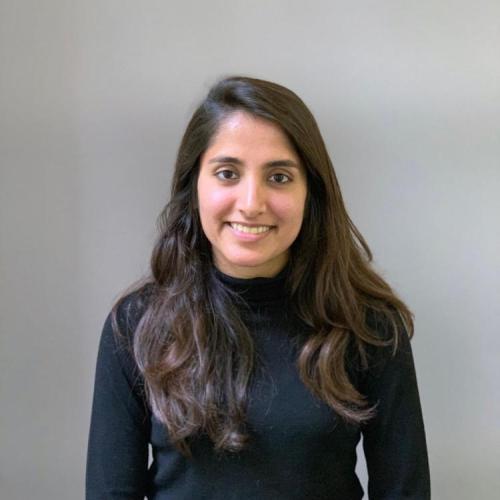 Smiling head shot of a woman with long dark brown hair wearing a long sleeved black turtleneck sweater.