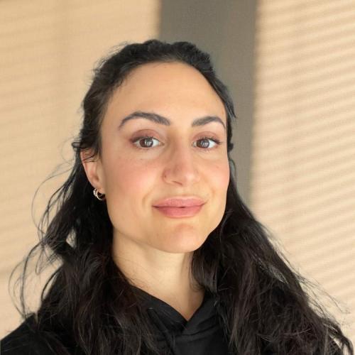 Photo of Gabrielle Benabdallah wearing a dark shirt and standing in front of a beige wall.