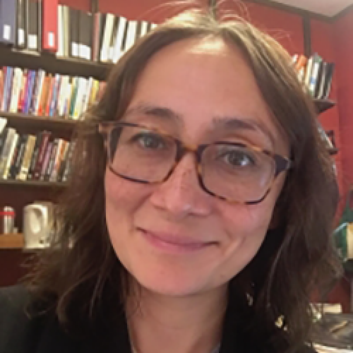 Portrait of Candice Rai sitting in front of a bookcase.