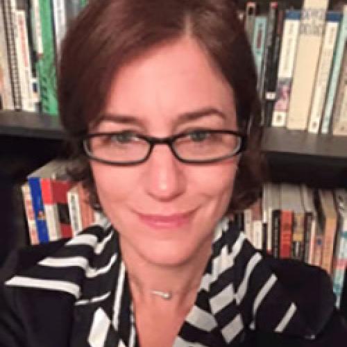 Portrait of Gillian Harkins sitting in front of a bookcase.