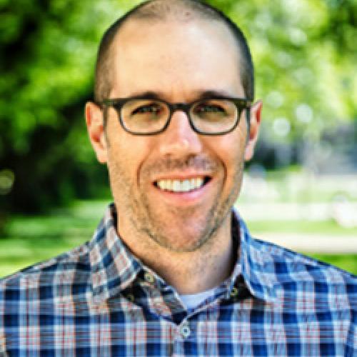 Portrait of Ian Schnee wearing glasses and standing outside.