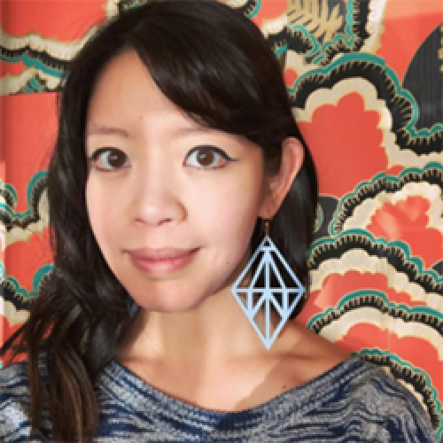 Jane Wong stands in front of a patterned wall wearing a grey shirt.