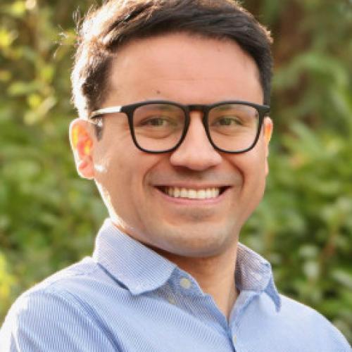 Jesús Hidalgo stands outside while wearing glasses and a blue collared shirt.