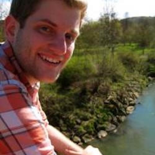 Justin Mohler looks at the camera while sitting in front of a river.