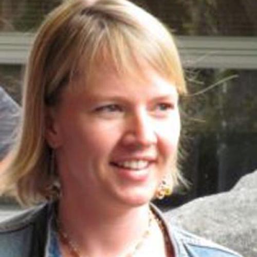 Janice Moskalik looks to the right and smiles while wearing a light shirt and denim jacket.