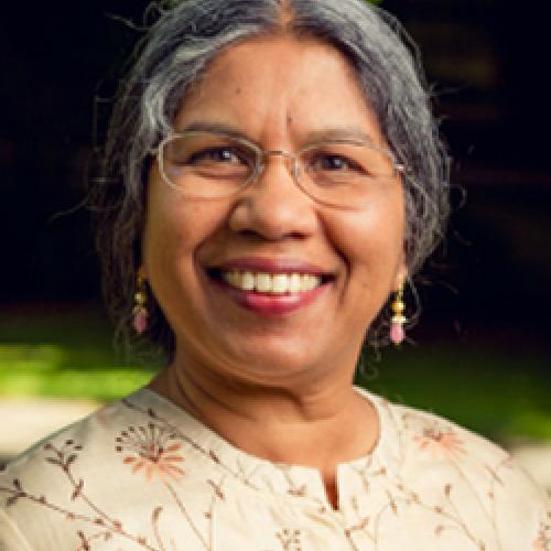 Priti Ramamurthy stands outside wearing glasses and a floral shirt.