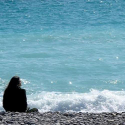 Sarah Ross sits on a beach looking toward the water.