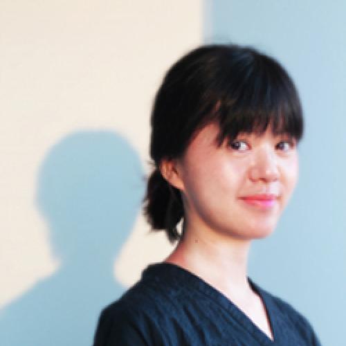 Ying-Hsiu Chou stands in front of a white wall wearing a dark shirt.