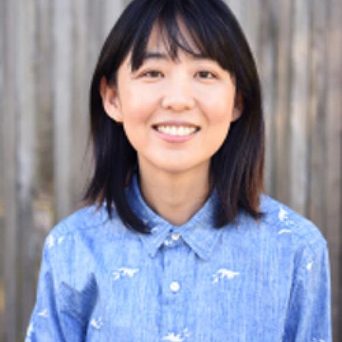 Portrait of Ellen Y. Chang standing in front of a blurred background and wearing a blue collared shirt.